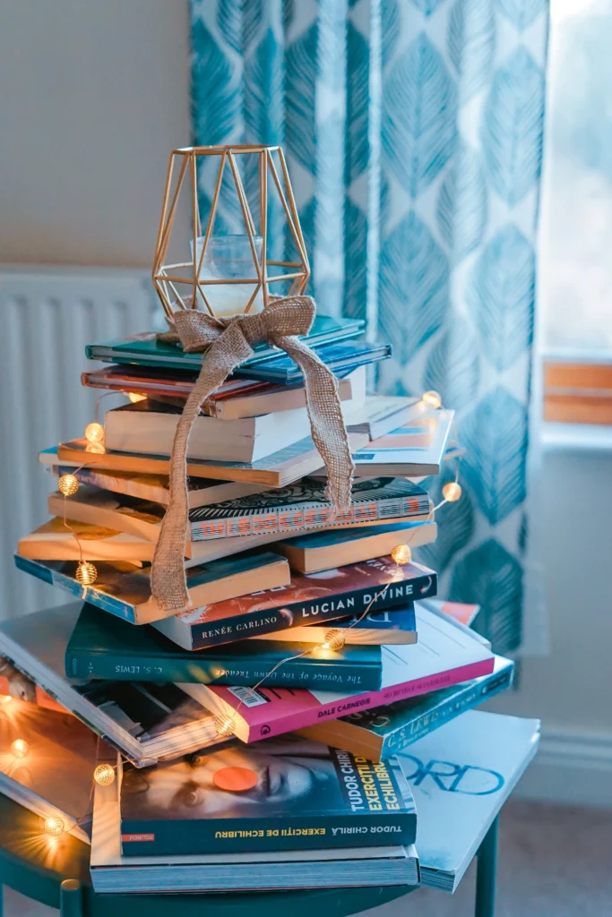 books piled up like a christmas tree with yellow lights