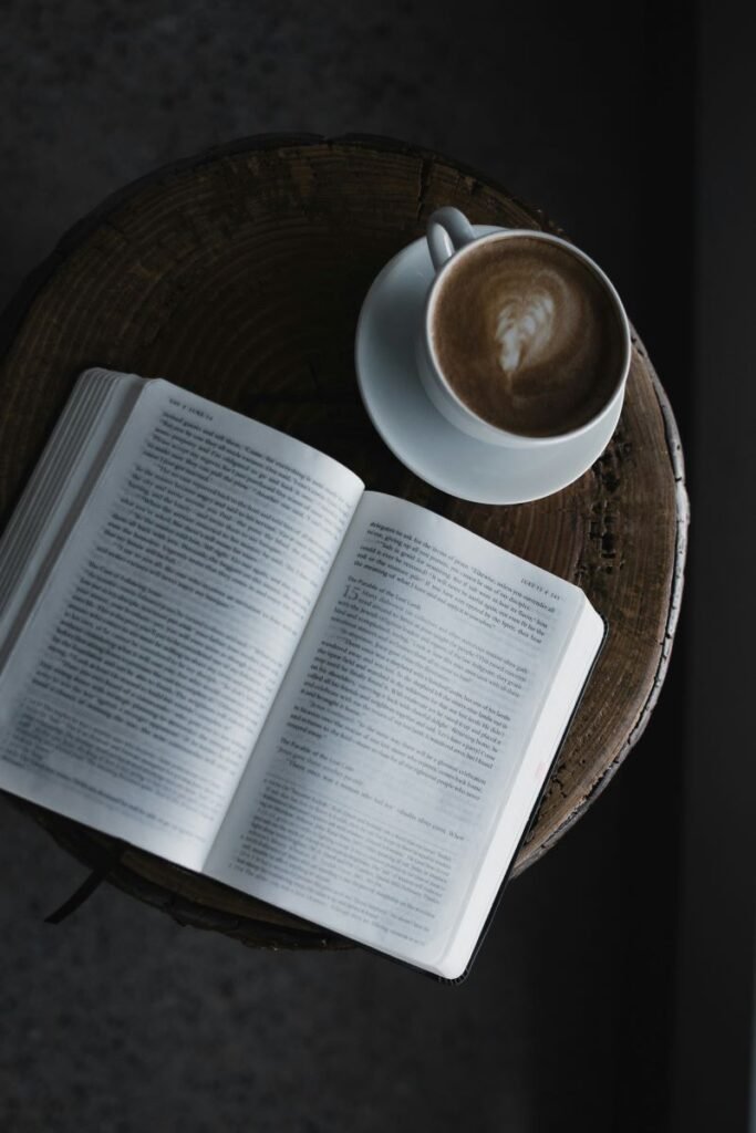 A religious book opened and placed on a table with a warm soothing coffee.