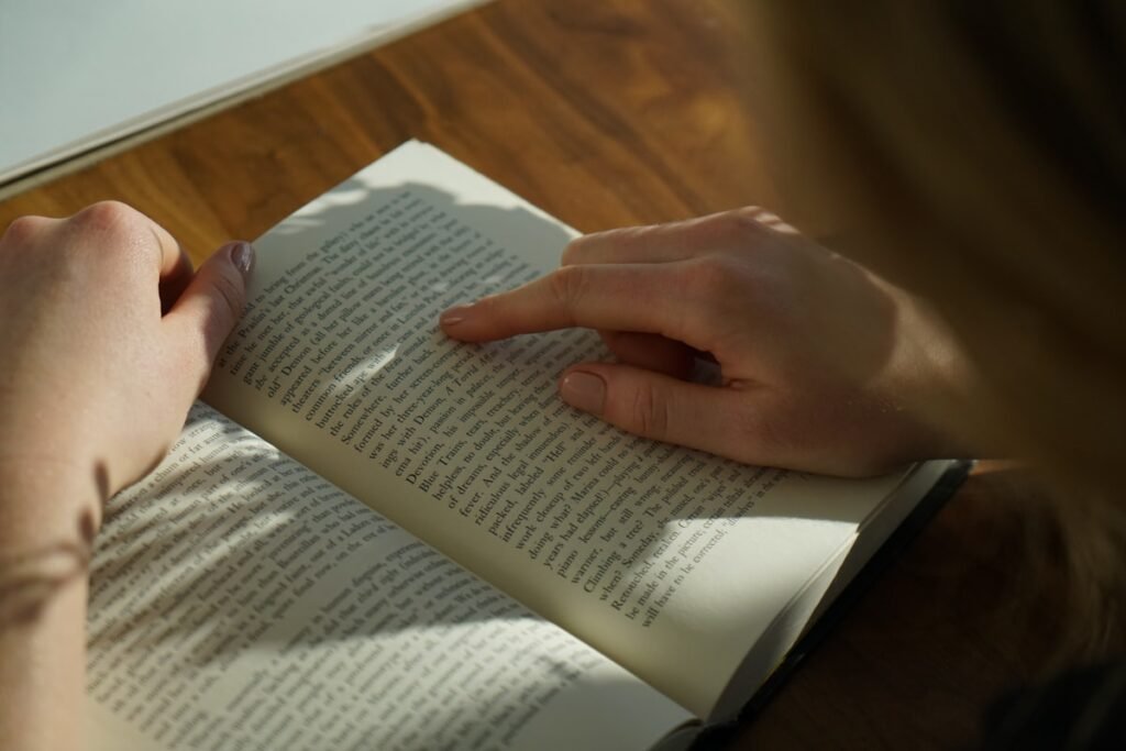 Person reading a physical book at a wooden table during the day
Physical Books vs. Digital Books image