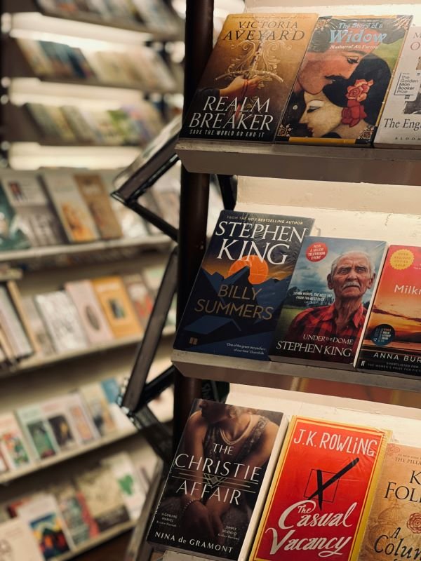 Display of bestselling fiction, thriller, and fantasy books on bookstore shelves featuring popular novels by renowned authors.