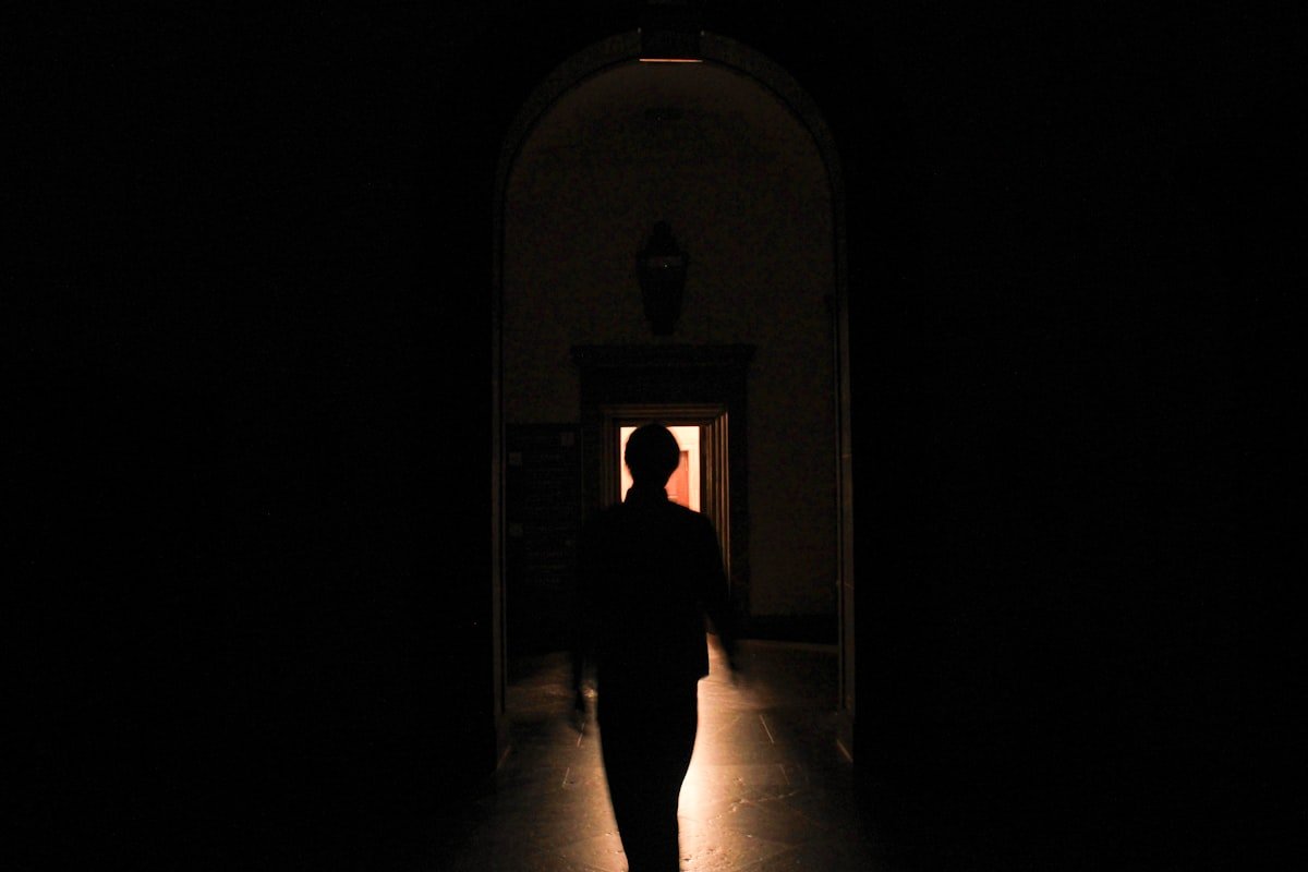 Silhouette of a person walking through a dark hallway