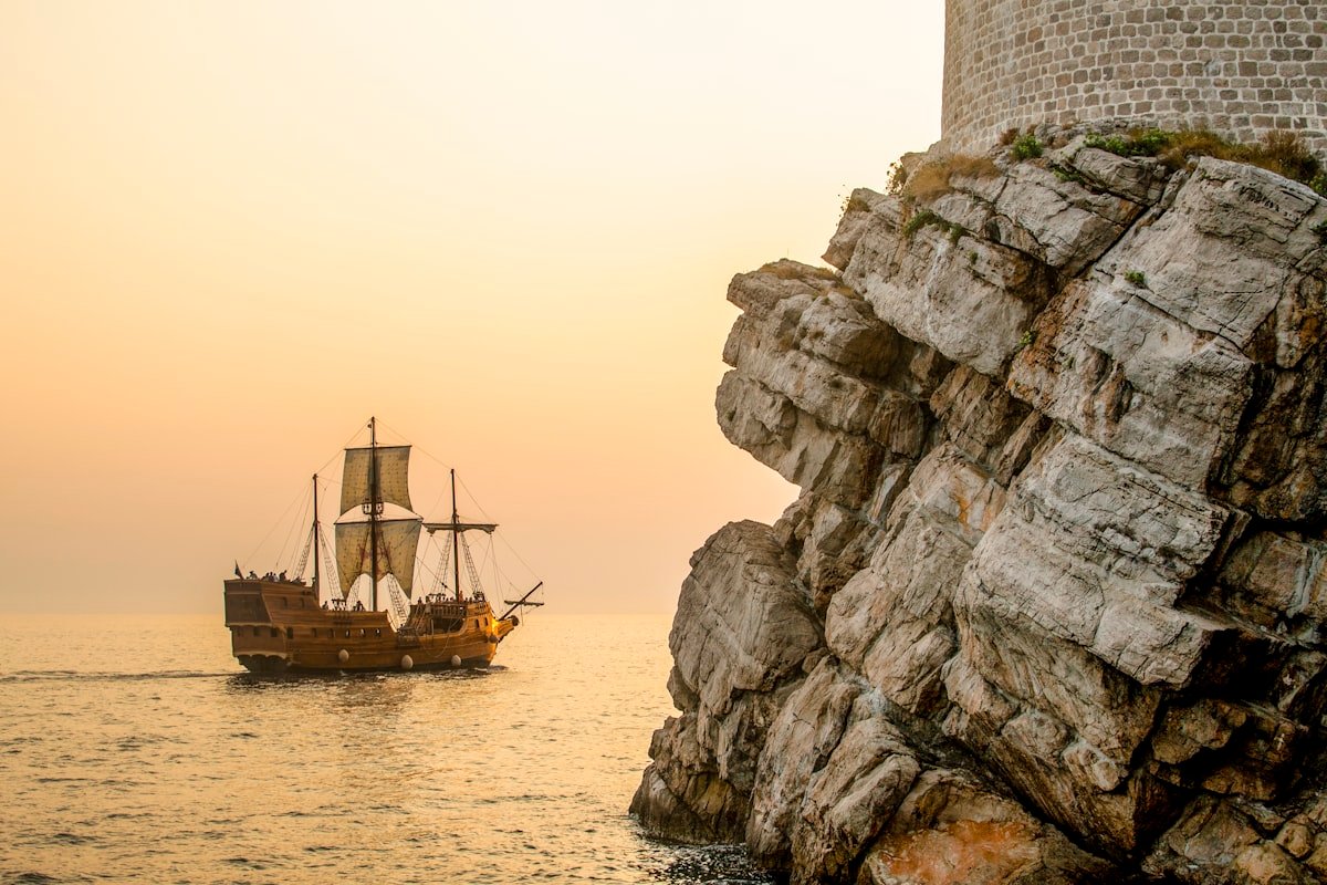 A boat sailing on the water near a rocky cliff